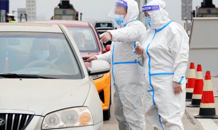 A staff member wearing personal protective equipment (PPE) directs drivers as they check people's nucleic acid test results and health codes at a highway toll station in Yantai, in China's eastern Shandong province on March 16, 2022. - - China OUT (Photo by AFP) / China OUT (Photo by STR/AFP via Getty Images)
